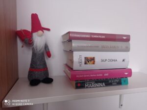 Na zdjęciu stos książek na półce i skandynawski gnomek.
