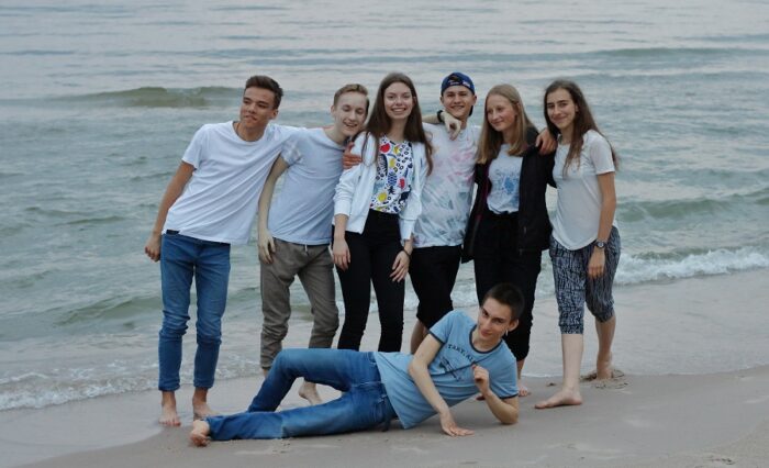 Na zdjęciu grupka młodzieży nad brzegiem morza.