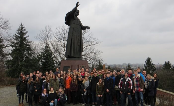 Na zdjęciu duża grupa młodzieży pod pomnikiem Jana Pawła II.