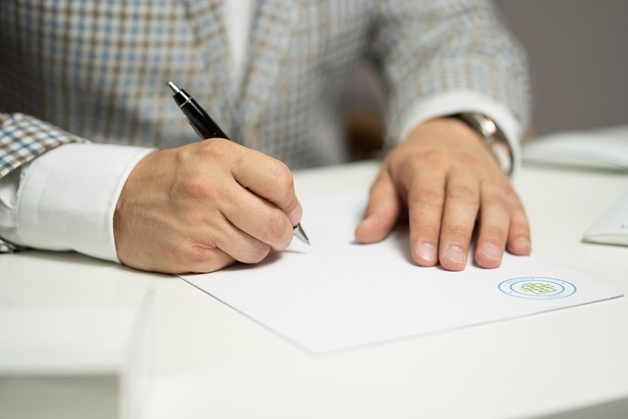 Na zdjęciu ręce osoby podpisującej dokument.
