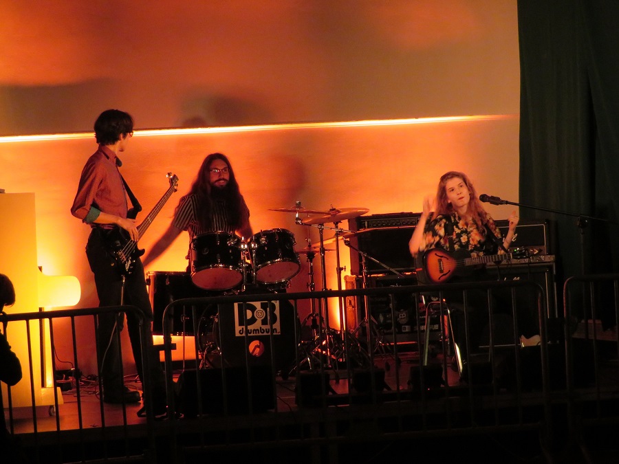Na zdjęciu jeden z zespołów muzycznych na scenie w pomarańczowej poświacie.