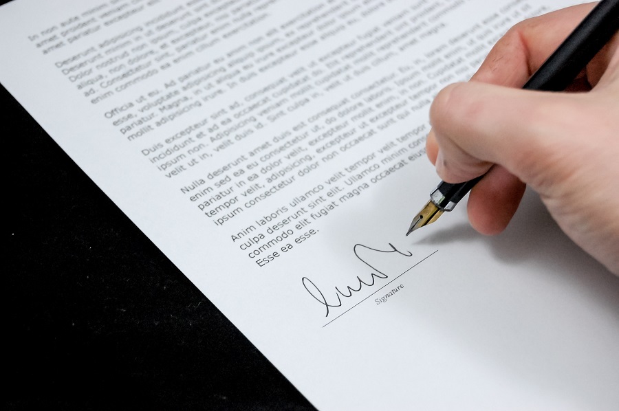 Na zdjęciu dłoń trzymająca wieczne pióro i podpisująca list.