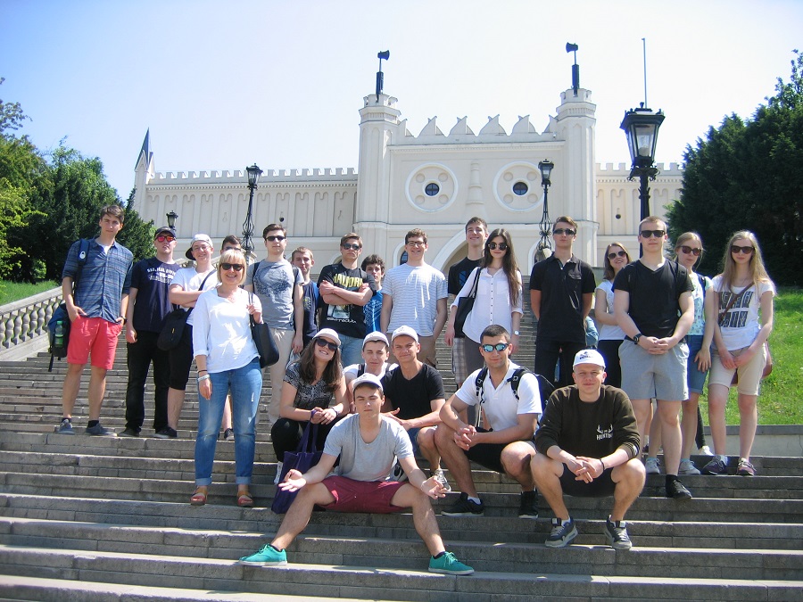 Na zdjęciu grupa uczniów na schodach, w tle biały pałacyk.