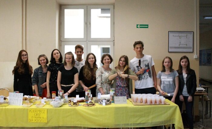 Na zdjęciu uczniowie organizujący kiermasz stoją za stołem pełnym ciast.