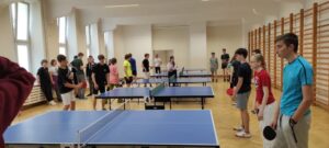 Na zdjęciu uczniowie w sali gimnastycznej przy stołach do ping ponga.