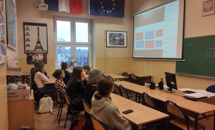 Na zdjęciu uczniowie w sali lekcyjnej słuchają wykładu online.