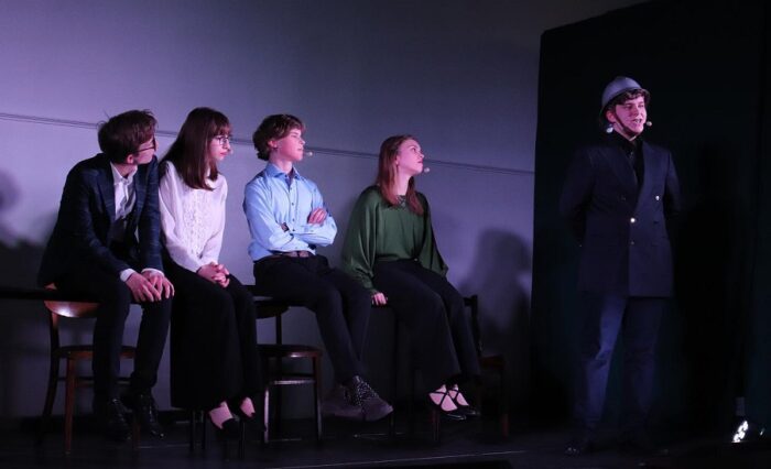 Na zdjęciu pięcioosobowa grupa uczniów na scenie podczas przedstawienia.