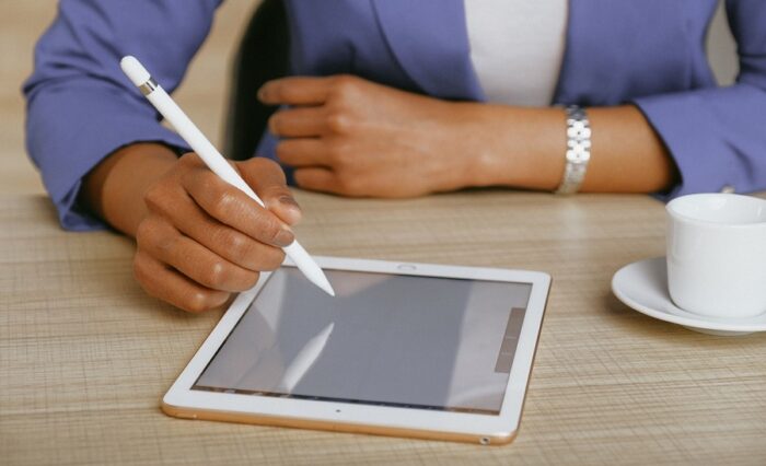 Na zdjęciu dłoń trzymająca rysik i pisząca na ekranie tableta.