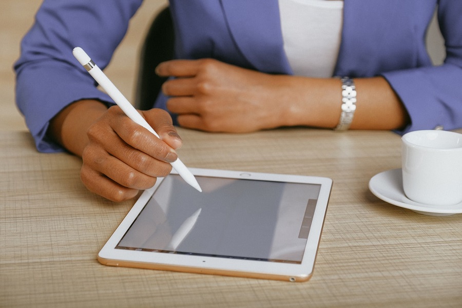 Na zdjęciu dłoń trzymająca rysik i pisząca na ekranie tableta.