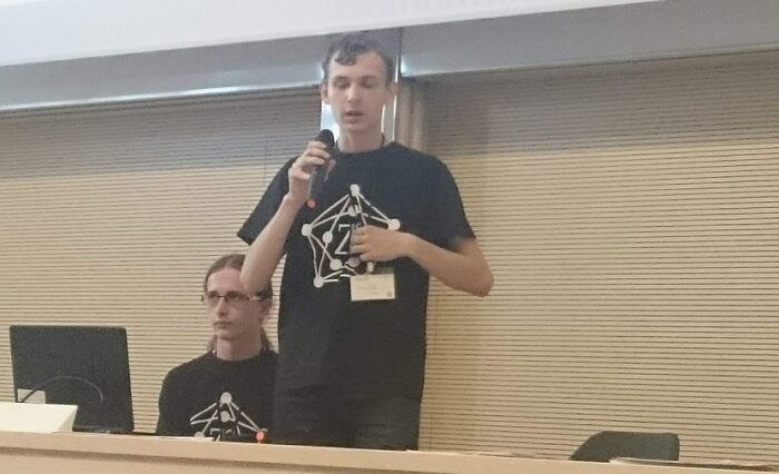 Na zdjęciu uczeń z mikrofonem podczas wystąpienia na konferencji.