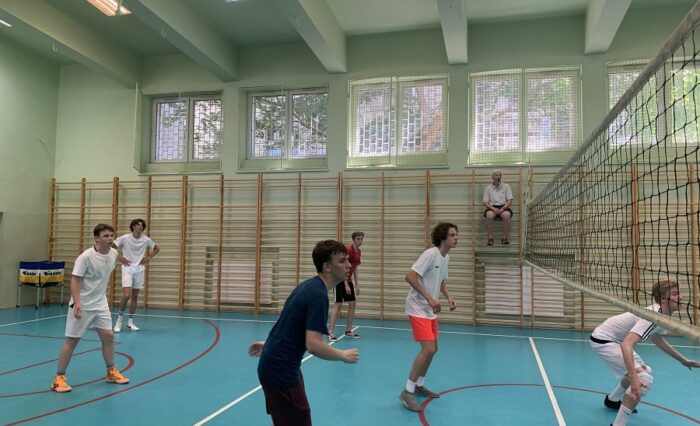 Na zdjęciu młodzież gra w siatkówkę w sali gimnastycznej.