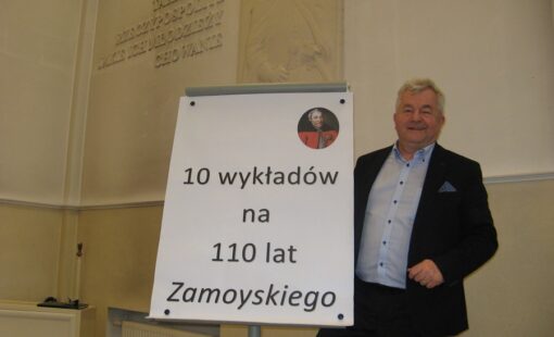 Na zdjęciu wykładowca stoi przy tablicy z napisem "10 wykładów na 110 lat Zamoyskiego".