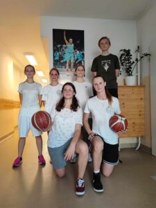 Na zdjęciu grupa dziewcząt z piłką do koszykówki. 