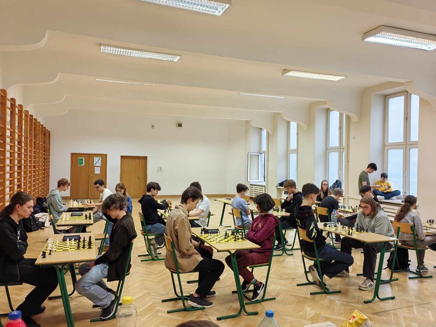 Na zdjęciu młodzież gra w szachy przy stolikach.